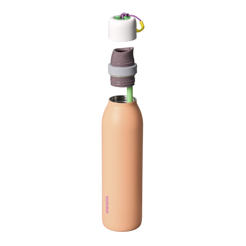 Owala FreeSip Twist 24oz in Peachy Keen, exploded view showing peach-orange body, white twist cap floating above with purple carry string and yellow carry string grip, mauve FreeSip spout, and green straw